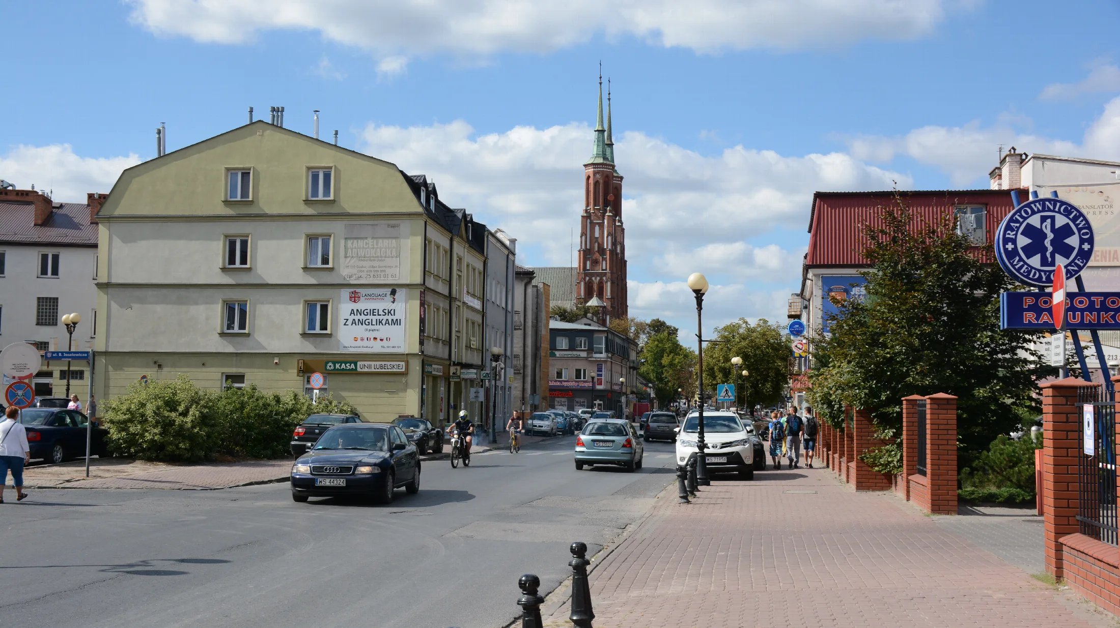 Widok na jedną z głównych ulic Siedlec z charakterystyczną miejską zabudową i kościelną wieżą
